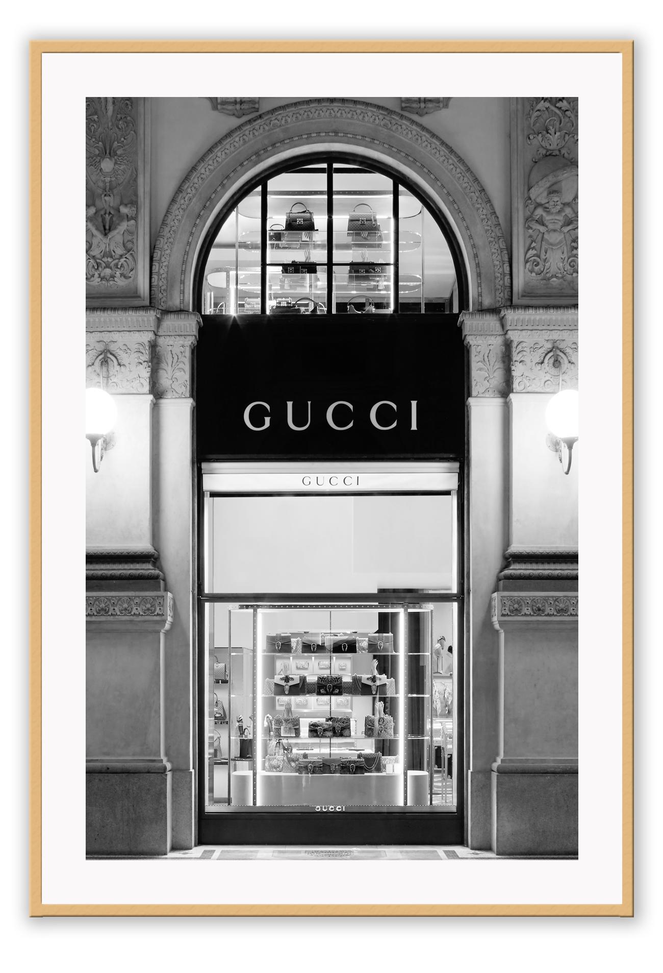 Fashion print with black and white Gucci shopfront faÔøΩade at night with ornamental lights and moulding.