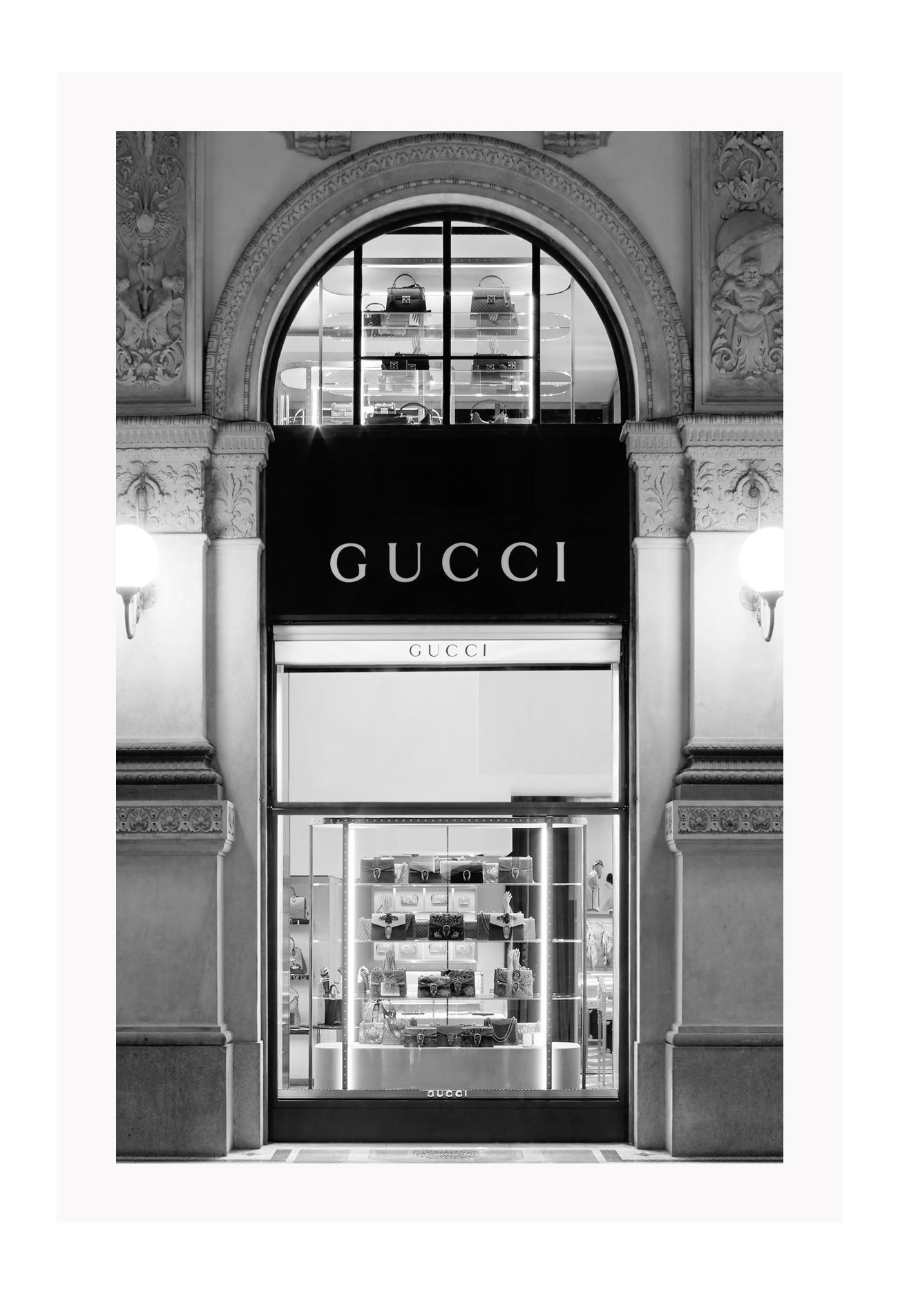 Fashion print with black and white Gucci shopfront faÔøΩade at night with ornamental lights and moulding.