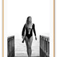 A black and white fashion wall art with Brazilian model Gisele Bundchen holding a surf board walking on timber wharf.