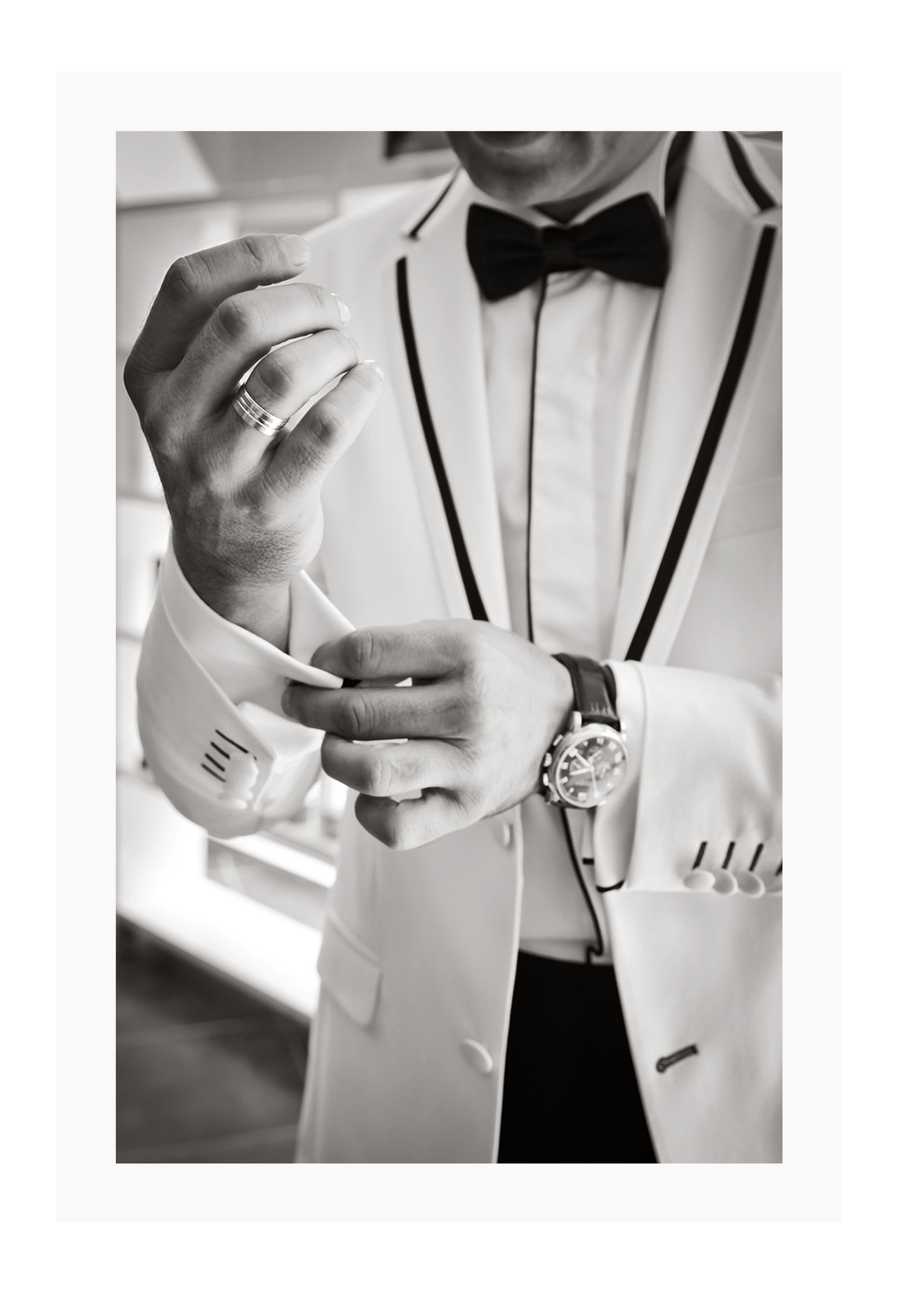 Photography fashion print man adjusting cufflinks on white suit jacket with expensive watch and bow tie 