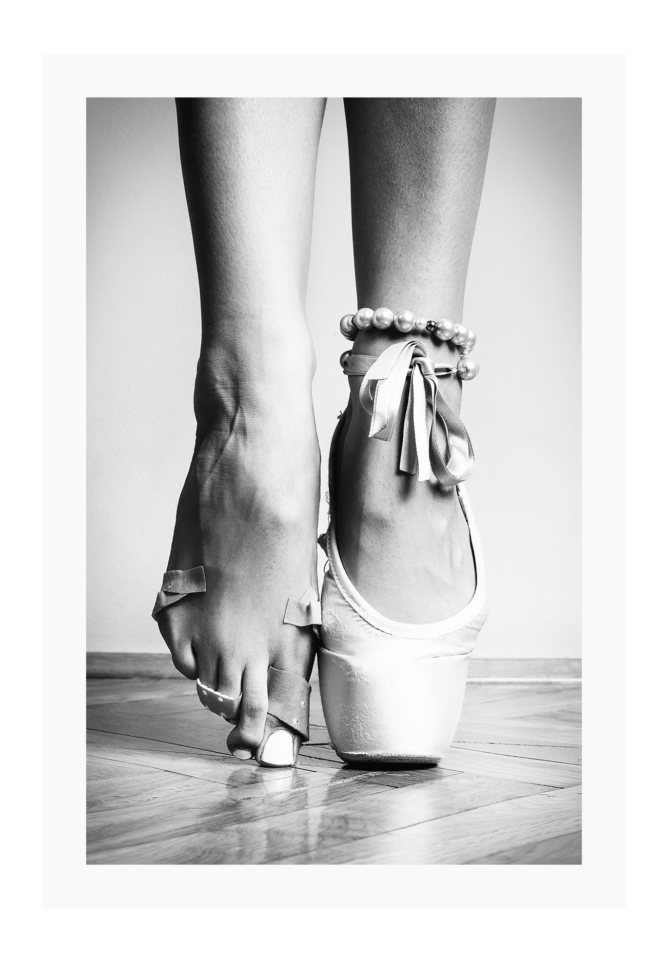 A vintage black and white wall art with a ballerina in point shoes close-up