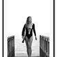 A black and white fashion wall art with Brazilian model Gisele Bundchen holding a surf board walking on timber wharf.