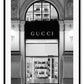 Fashion print with black and white Gucci shopfront faÔøΩade at night with ornamental lights and moulding. 