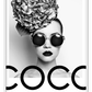 A black and white fashion photographic wall art of a lady holding balloon leaning on a scandi bike, riding on the writing coco chanel I don't do fashion I am fashion. 