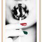 Black and white modern print featuring a woman sucking a lollypop with one green one red finger nail and striped lipstick.