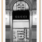 Fashion print with black and white Gucci shopfront faÔøΩade at night with ornamental lights and moulding. 