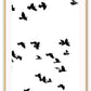 A black and white wall art with black sky birds in white sky. 