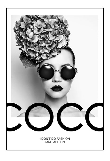 A black and white fashion photographic wall art of a lady holding balloon leaning on a scandi bike, riding on the writing coco chanel I don't do fashion I am fashion. 